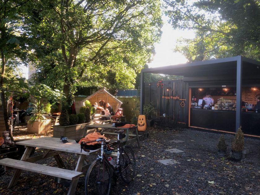 Bicycle leaning against a wooden picnic table, outdoor coffee shop in the background