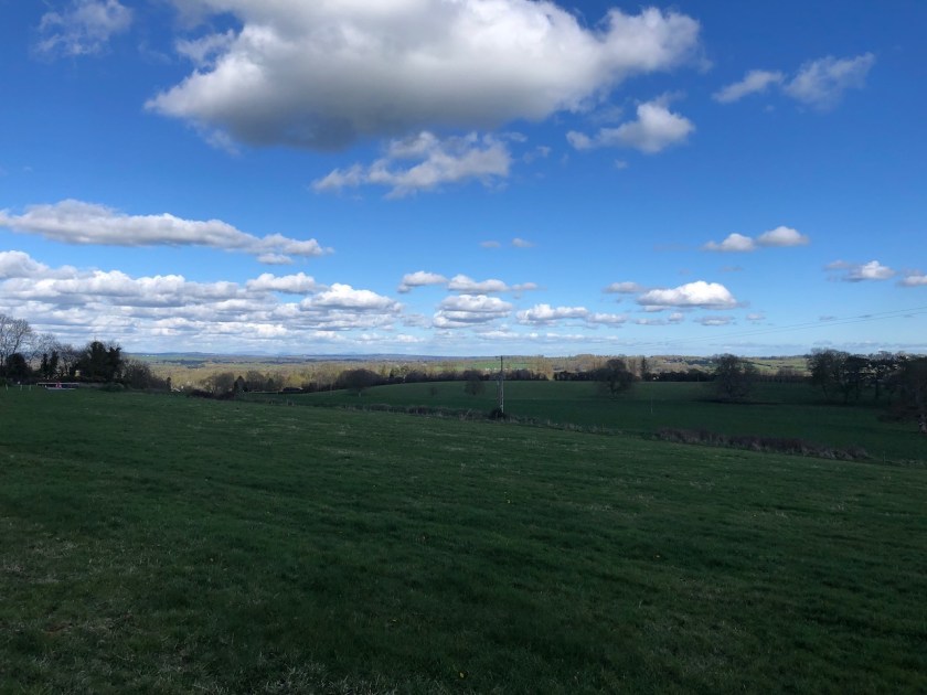 The view looking north-east from the Hill of Tara — green fields under a blue sky with scattered cloud