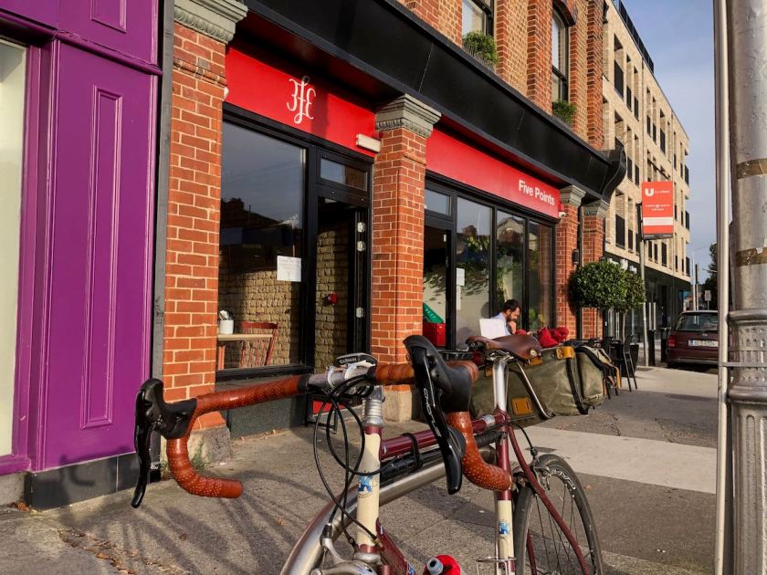 Oblique angle shot of bicycle locked to rack with Five Points cafe in background